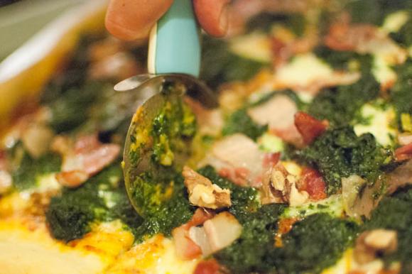 krojenie pizzy ze szpinakiem, serem pleśniowym i orzechami krojenie pizzy ze szpinakiem, serem pleśniowym i orzechami